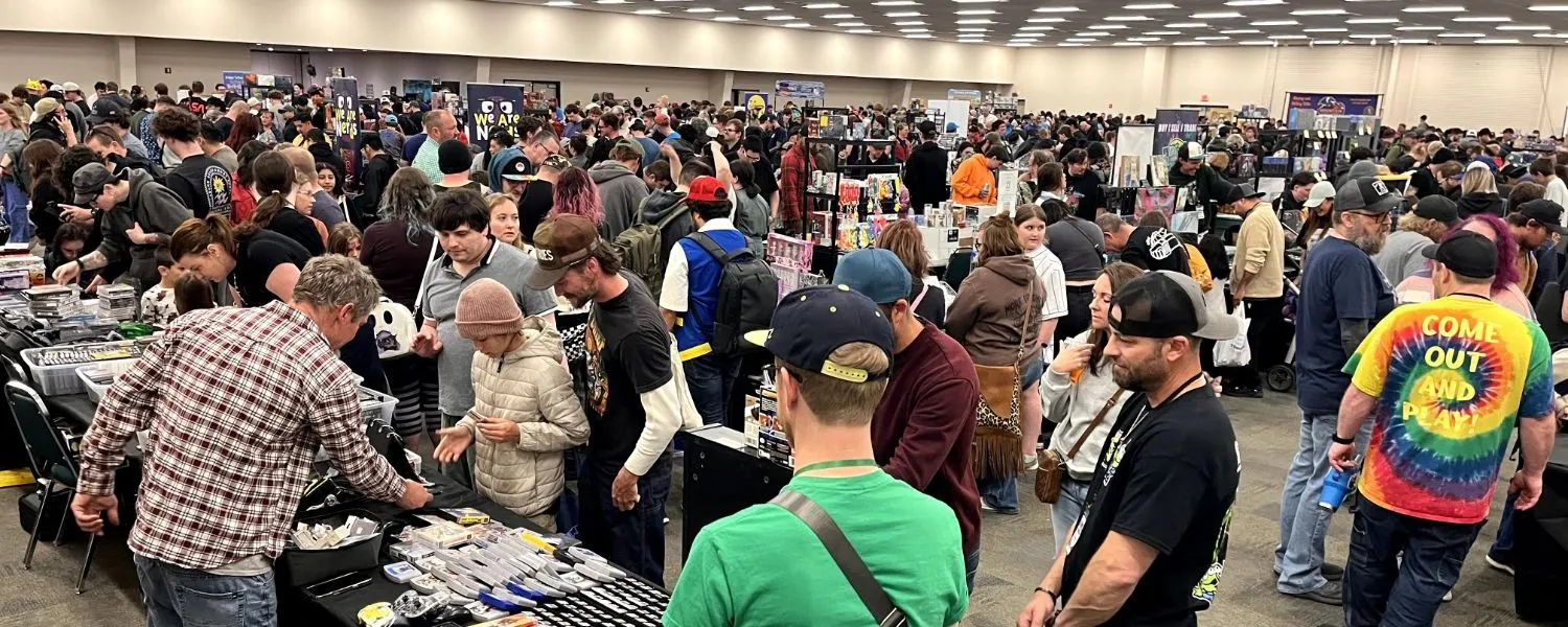 A packed show floor, crowds browsing rows of vendor tables